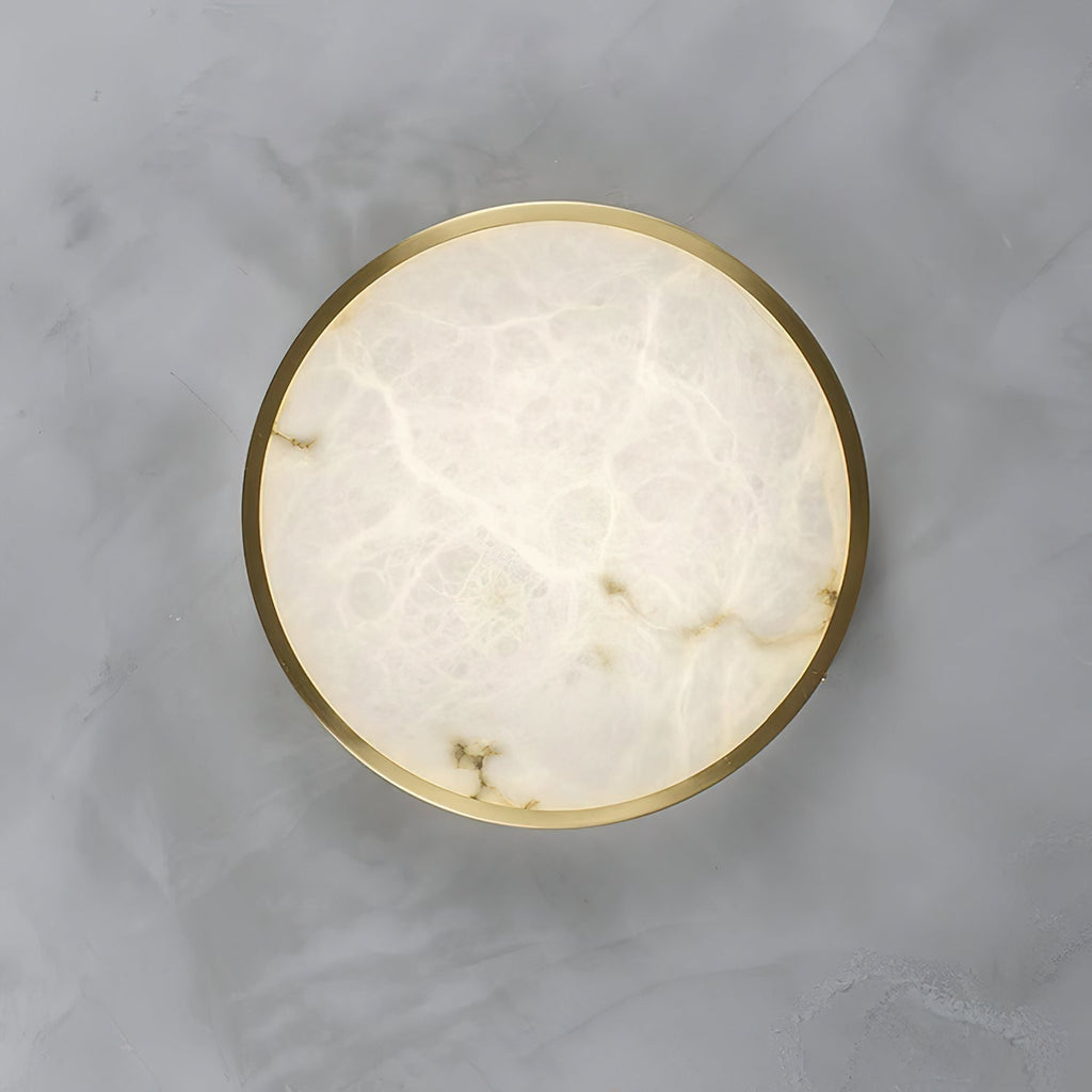 The alabaster face of the round Clérachic flush ceiling light fills the frame, its grey veining ringed by a thin brass rim.