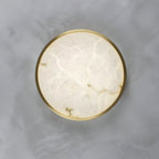 The alabaster face of the round Clérachic flush ceiling light fills the frame, its grey veining ringed by a thin brass rim.