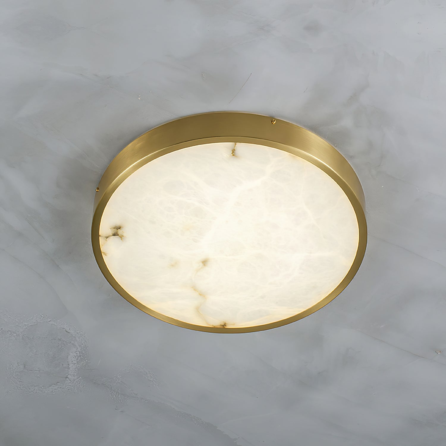 Round Clérachic alabaster flush ceiling light lit on a marble ceiling, the stone glowing from the LED behind it.