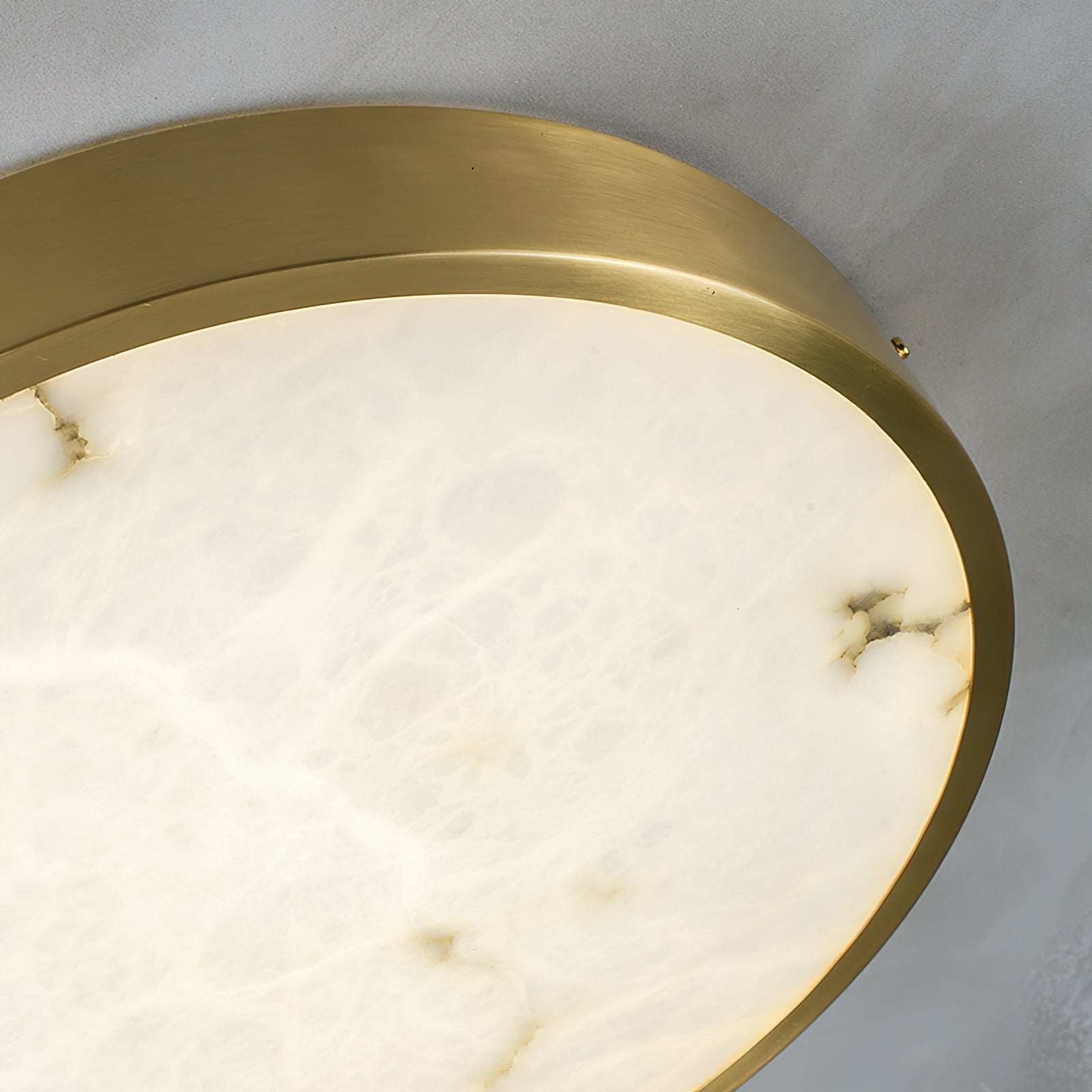 Close crop of the round Clérachic alabaster flush ceiling light, showing the brass band edge and the stone's soft veining.