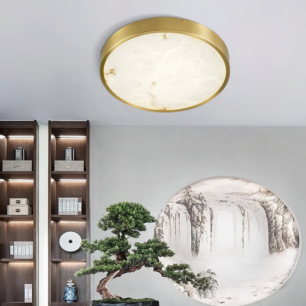 Round Clérachic alabaster flush ceiling light lighting a room with backlit shelving, a bonsai and a landscape mural.