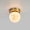Globe-shade Clérachic flush mount ceiling light glowing softly against a smooth grey ceiling, brass canopy tight to the plaster