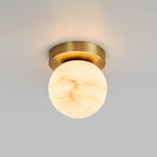 Globe-shade Clérachic flush mount ceiling light glowing softly against a smooth grey ceiling, brass canopy tight to the plaster