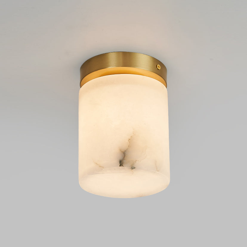 The cylinder version of the Clérachic alabaster ceiling light seen head-on, warm light filling the stone above a hallway
