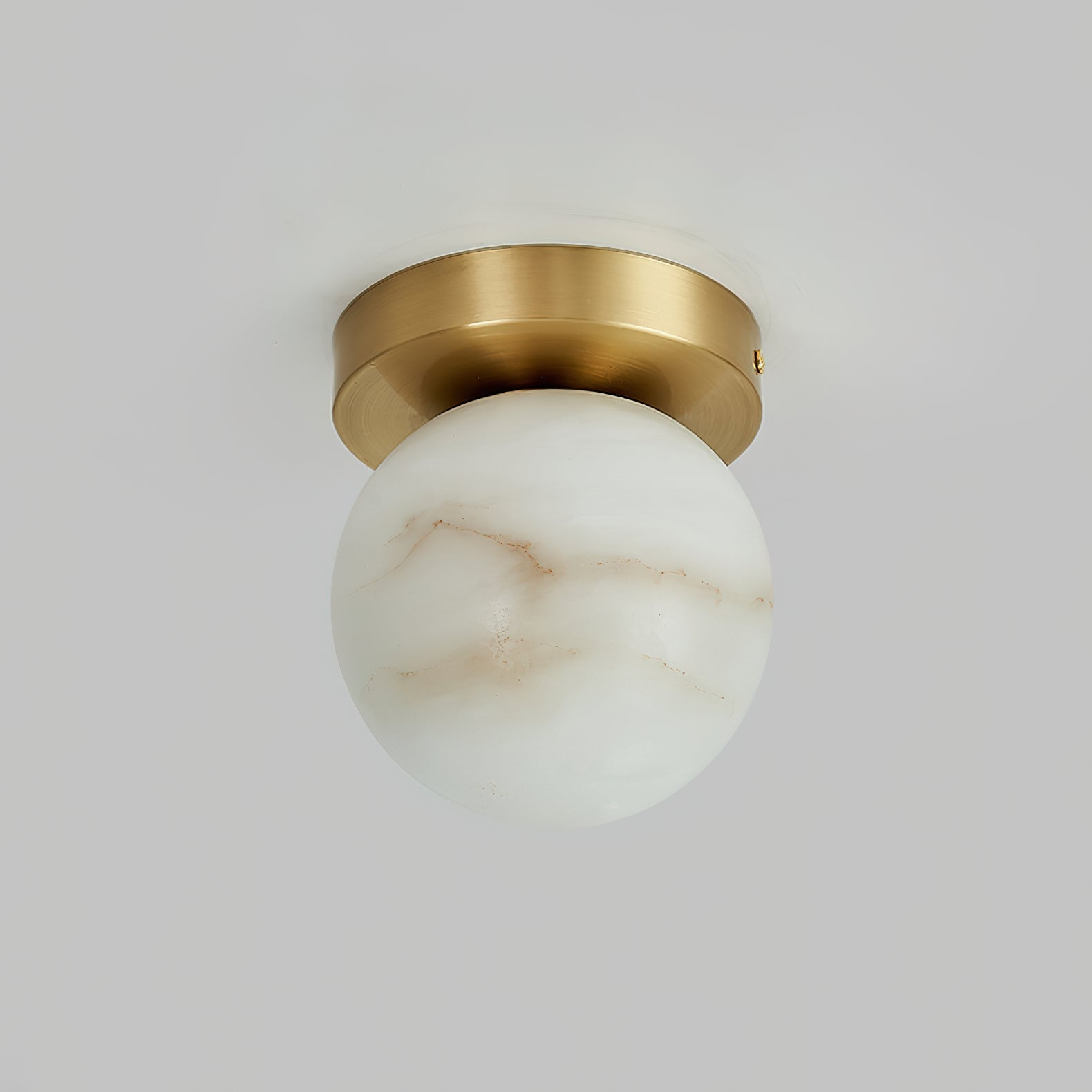 Clérachic alabaster flush mount ceiling light unlit, the pale globe showing fine rust-coloured veins under a brushed brass canopy