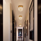 Three Clérachic alabaster globe ceiling lights down a narrow corridor hung with framed mirrors and a console table at the end