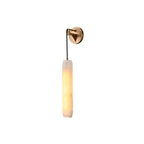 Clérachic alabaster flute wall sconce on a plain studio backdrop, brass plate above a warm-lit fluted stone tube.