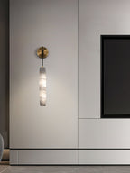 Clérachic sconce mounted on pale joinery, its unlit alabaster reading as carved stone beside a black niche.
