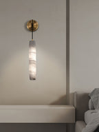 The Clérachic sconce above a floating stone ledge, casting a soft pool of light down the plaster wall.