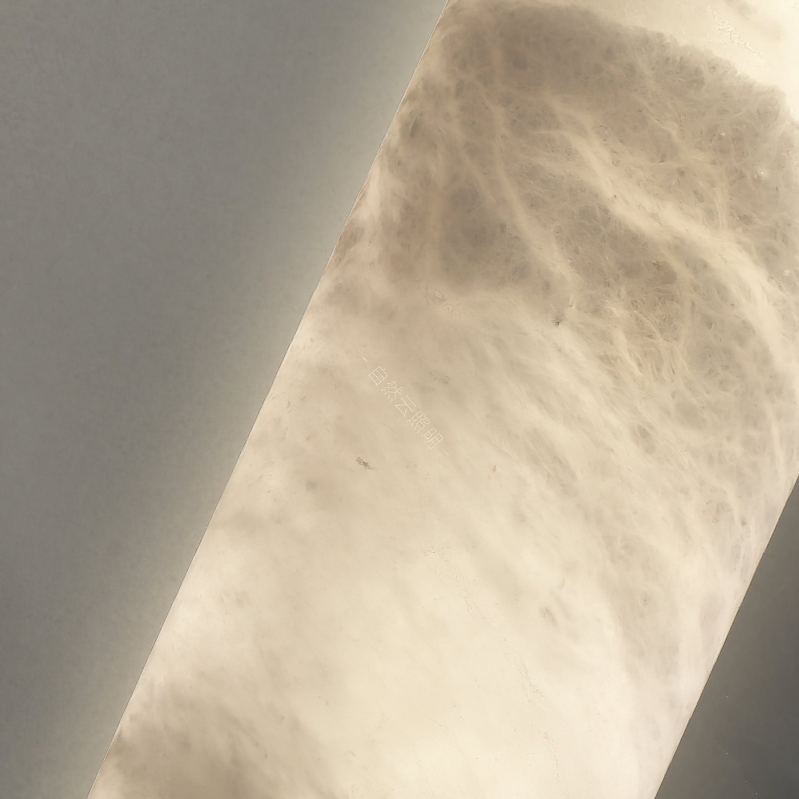Macro of the Clérachic alabaster shade, backlight picking out cloudy grey veining right across the stone.