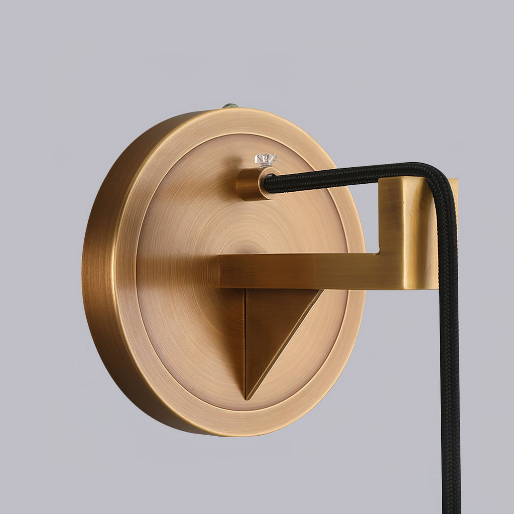 The Clérachic brass wall plate in close-up, its triangular bracket and braided black cord fixed to the canopy.