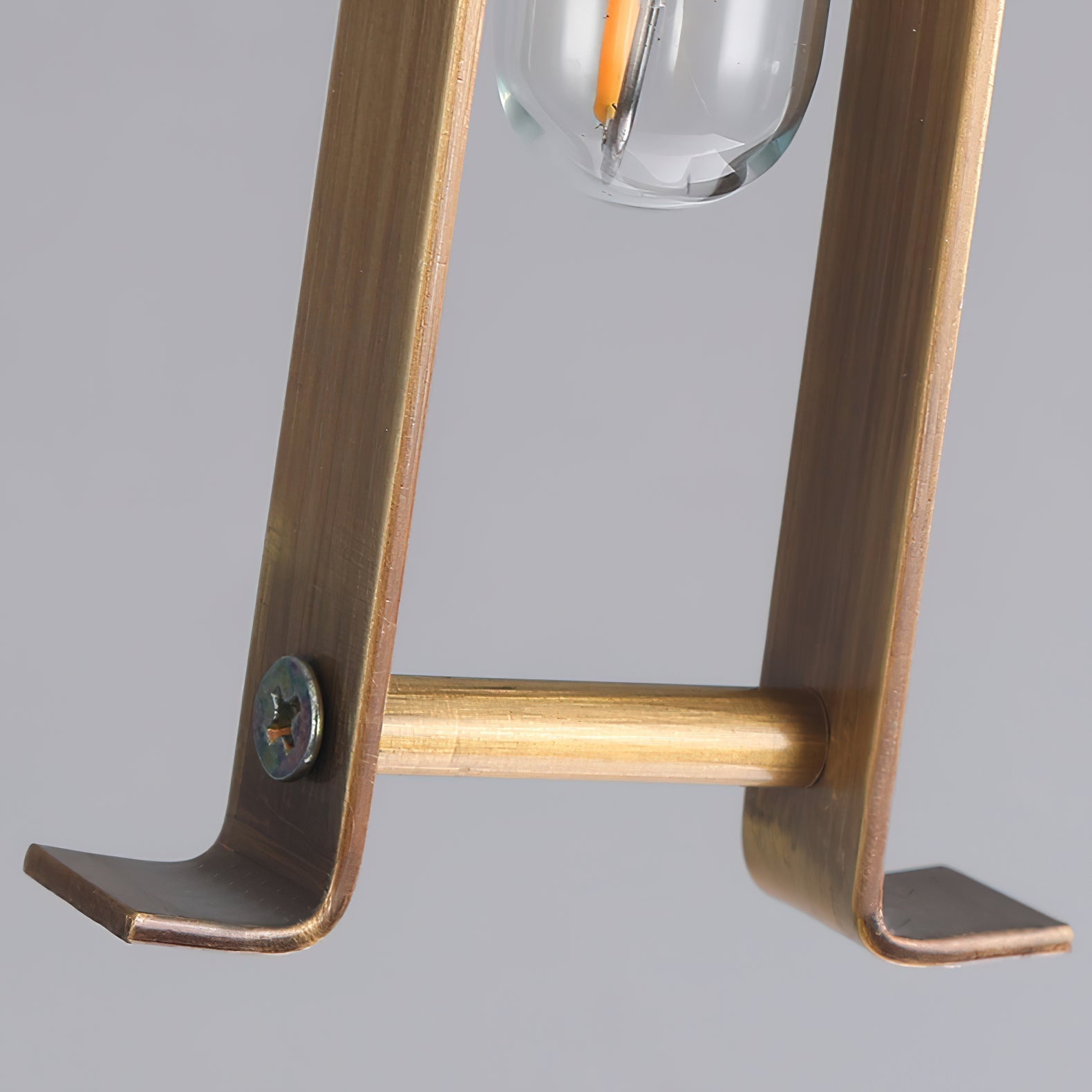 Clérachic brass arm detail, showing the machined bracket, exposed fixing screw and warm brushed finish.