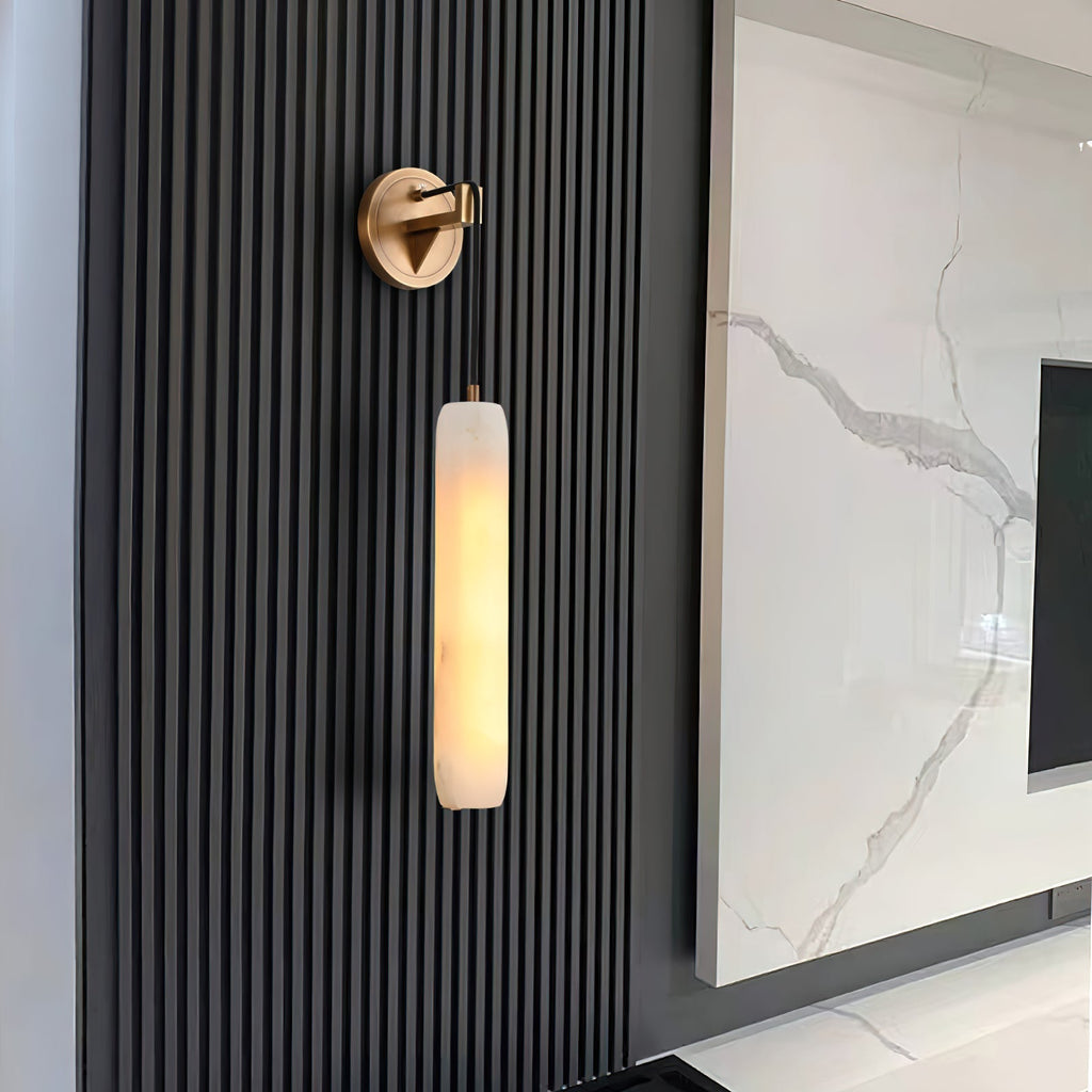The Clérachic sconce on a black fluted timber wall, its warm column set against a veined marble media panel.