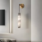 Clérachic sconce on a white bedroom wall next to a mounted screen, the alabaster unlit and softly grey.