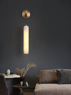 The Clérachic sconce against a charcoal living-room wall above a side table of dried grasses and a low sofa.