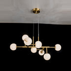 The nine-light Clérachic Alabaster Globe Chandelier, its staggered stone spheres glowing above a dark dining room wall.
