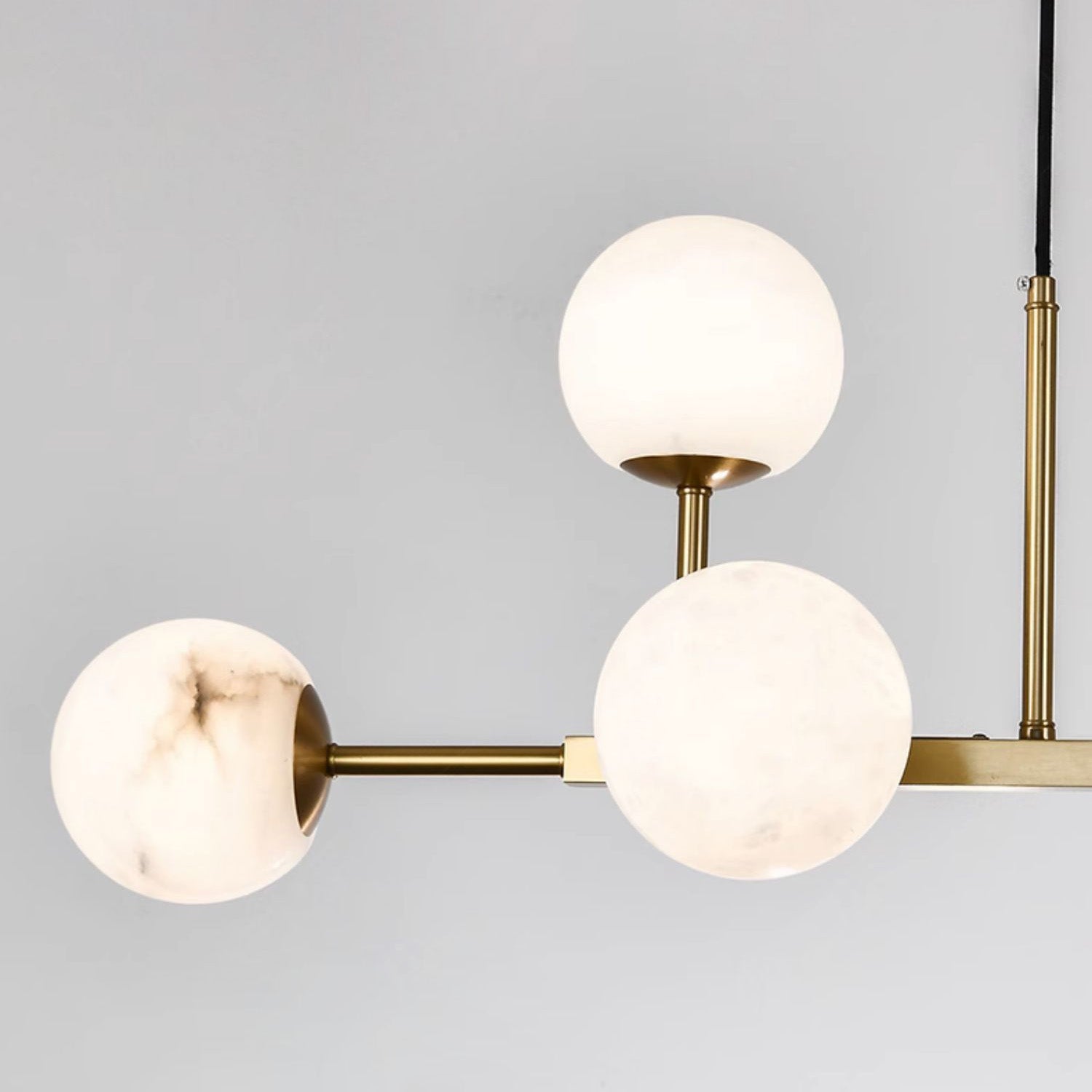 Close view of three globes on the Clérachic Alabaster Globe Chandelier, grey veining running through the polished stone.