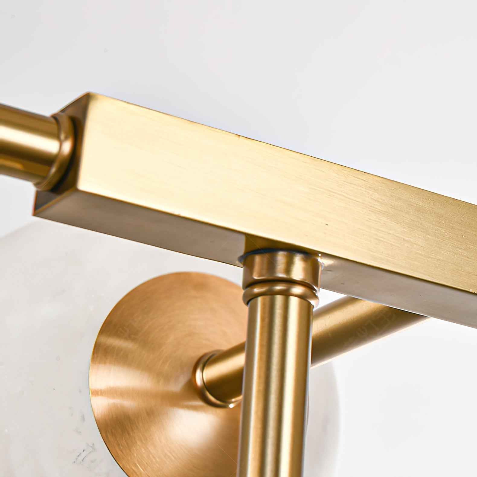 Square-section brass arm meeting a drop rod on the Clérachic Alabaster Globe Chandelier, brushed finish shown up close.