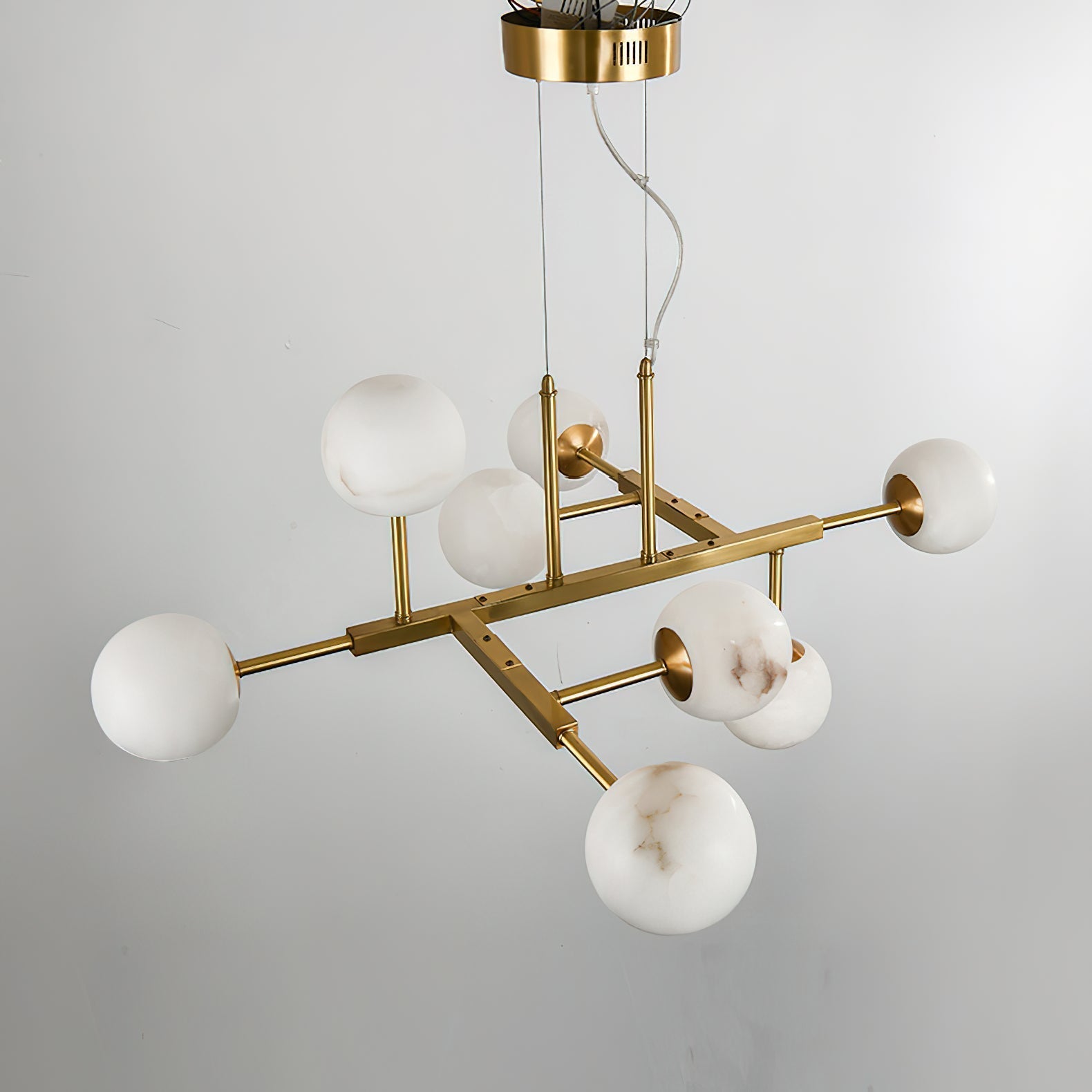 Angled view of the Clérachic Alabaster Globe Chandelier showing the branching brass armature and its twin drop rods.