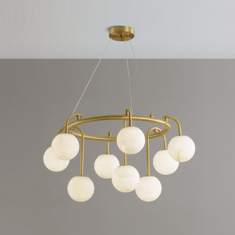 Clérachic Alabaster Globe Chandelier in its nine-light form, staggered stone globes riding a brass ring against a grey studio wall.