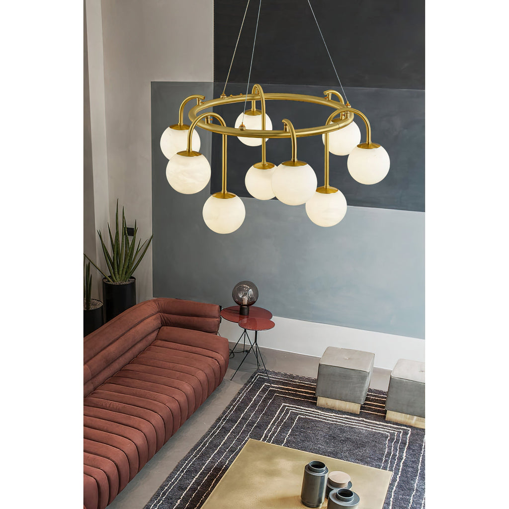 A nine-light Clérachic Alabaster Globe Chandelier glowing warm over a terracotta sofa and striped rug in a concrete-walled lounge.