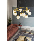 A nine-light Clérachic Alabaster Globe Chandelier glowing warm over a terracotta sofa and striped rug in a concrete-walled lounge.