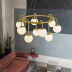 The Clérachic Alabaster Globe Chandelier unlit in a painted concrete lounge, nine stone globes above a rust sofa and potted plants.