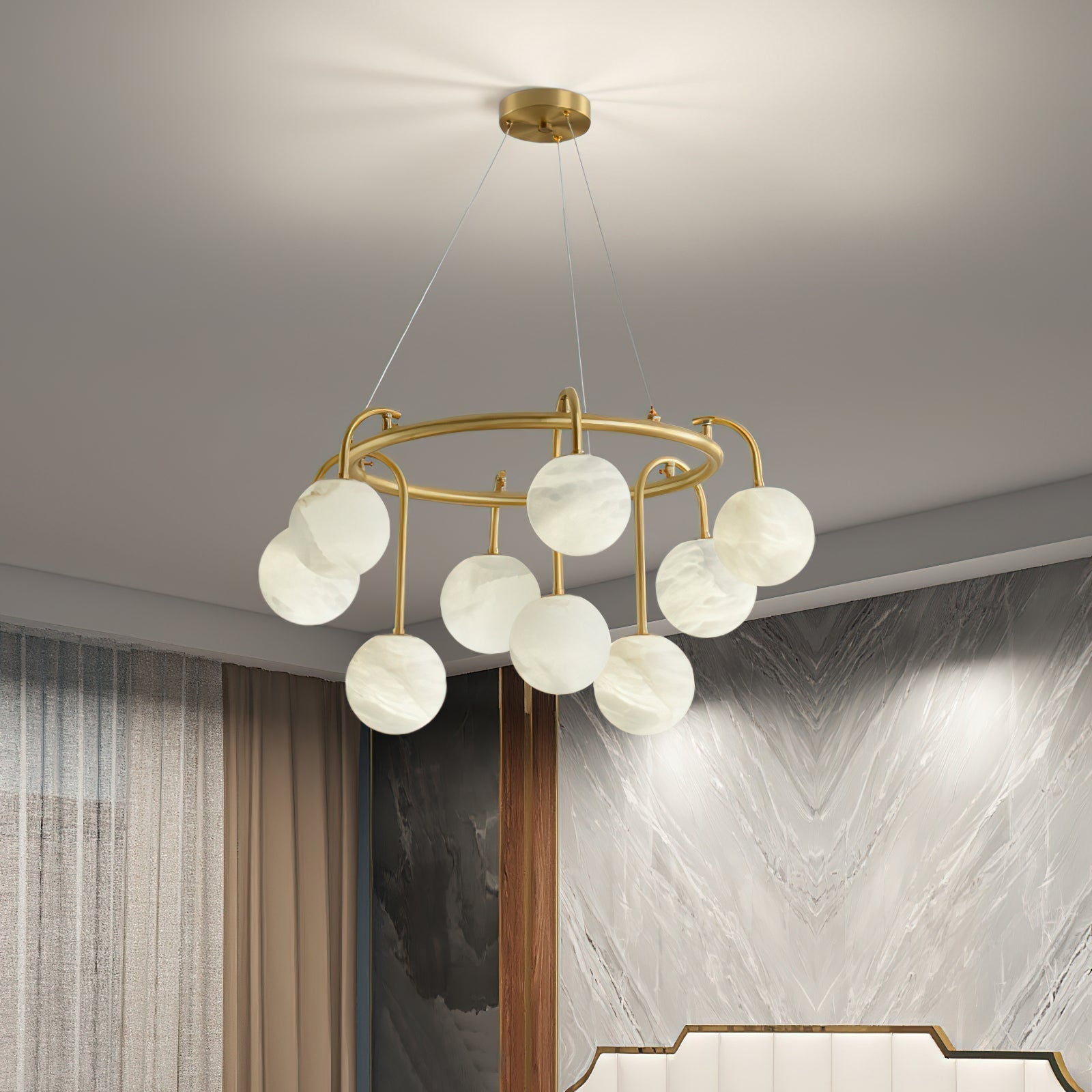 Clérachic Alabaster Globe Chandelier lit in a bedroom corner, its stone globes glowing beside a veined marble feature wall.