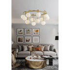 The Clérachic Alabaster Globe Chandelier lit over a grey sofa and round brass table, below a six-frame gallery wall.