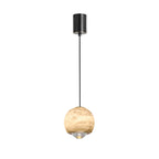 Studio view of the Clérachic Alabaster Globe Pendant Light, a brass band under the stone globe holding the clear stepped lens that beams down.