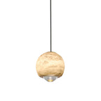 Close studio crop of the Clérachic Alabaster Globe Pendant Light, grey veining across the warm stone and the stepped lens throwing light down.