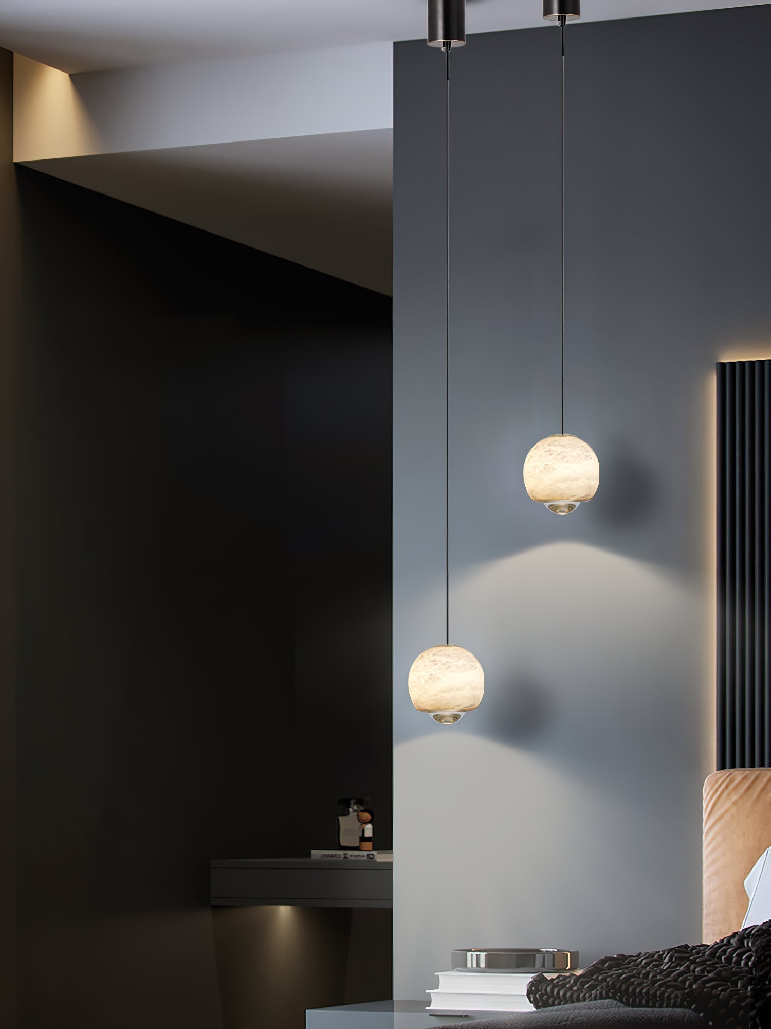 Two Clérachic Alabaster Globe Pendant Lights hung at staggered heights on a dark wall, small warm globes reading clearly against the shadow.