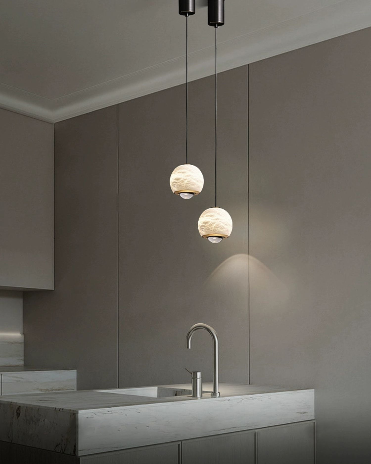 Clérachic Alabaster Globe Pendant Lights hung as a pair over a marble kitchen island, lighting the tap and counter from a high ceiling.