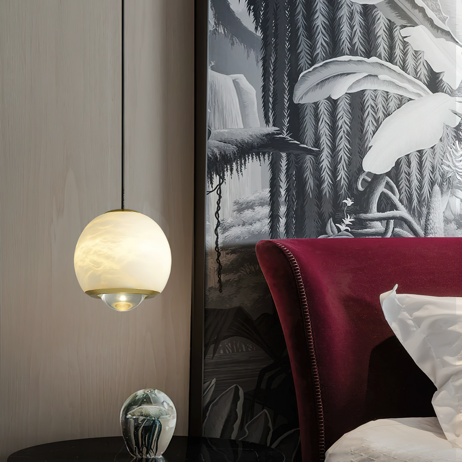 Clérachic Alabaster Globe Pendant Light glowing against pale wood panelling, beside a red velvet headboard and a black bedside table.