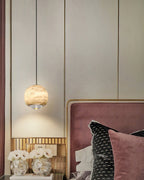 Clérachic Alabaster Globe Pendant Light against cream panelling with brass reveals, hung beside a pink velvet headboard and white anemones.