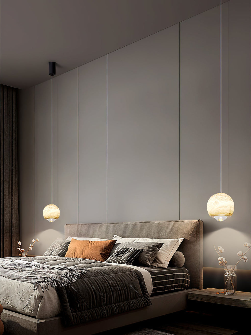 Two Clérachic Alabaster Globe Pendant Lights at different drops flanking a bed in a dim panelled bedroom, each pooling light on the wall.