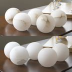 Five loose globes for the Clérachic Alabaster Globe Pendant Light lined up on a dark table, each carrying its own veining pattern.