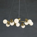 The brass ring of the Clérachic Alabaster Globe Ring Chandelier seen at an angle, chalk-white globes unlit in a grey room.