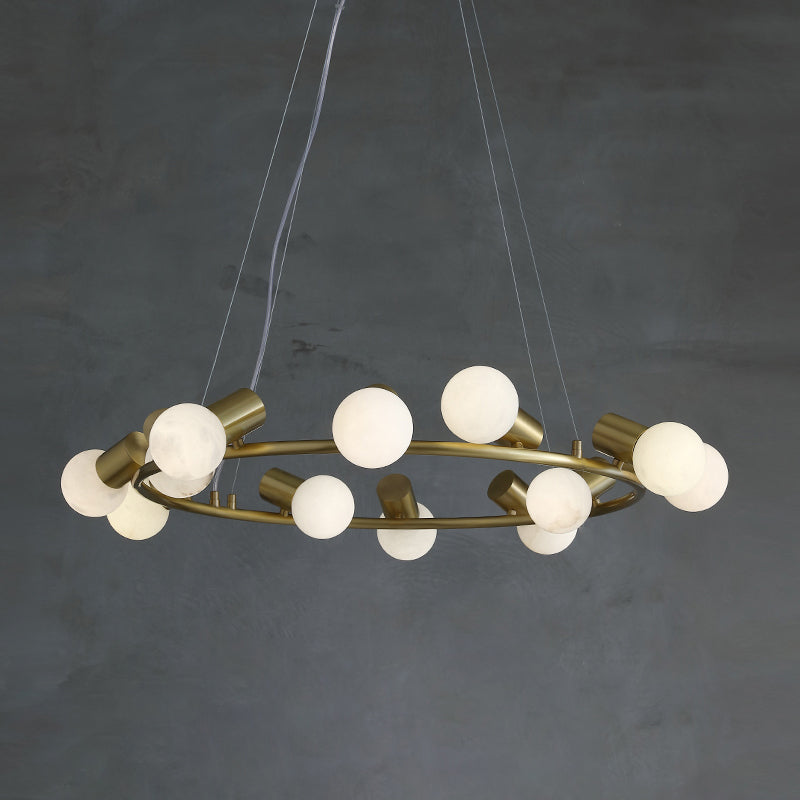 Alabaster spheres and brass sockets alternate around the ring of the Clérachic Alabaster Globe Ring Chandelier on a grey wall.