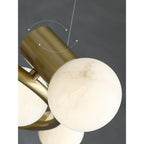 Grey veining runs through one stone globe on the Clérachic Alabaster Globe Ring Chandelier, held in its angled brass socket.
