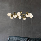 Clérachic Alabaster Globe Ring Chandelier hanging above a dark green leather sofa against a grey plaster living-room wall.