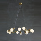 Clérachic Alabaster Globe Ring Chandelier hung low in a dim grey room, the brass ring catching light while the globes stay off.