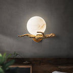 The Clérachic Alabaster Globe Wall Sconce lit on a grey plaster wall above a reclaimed wood sideboard, the stone glowing honey-warm.