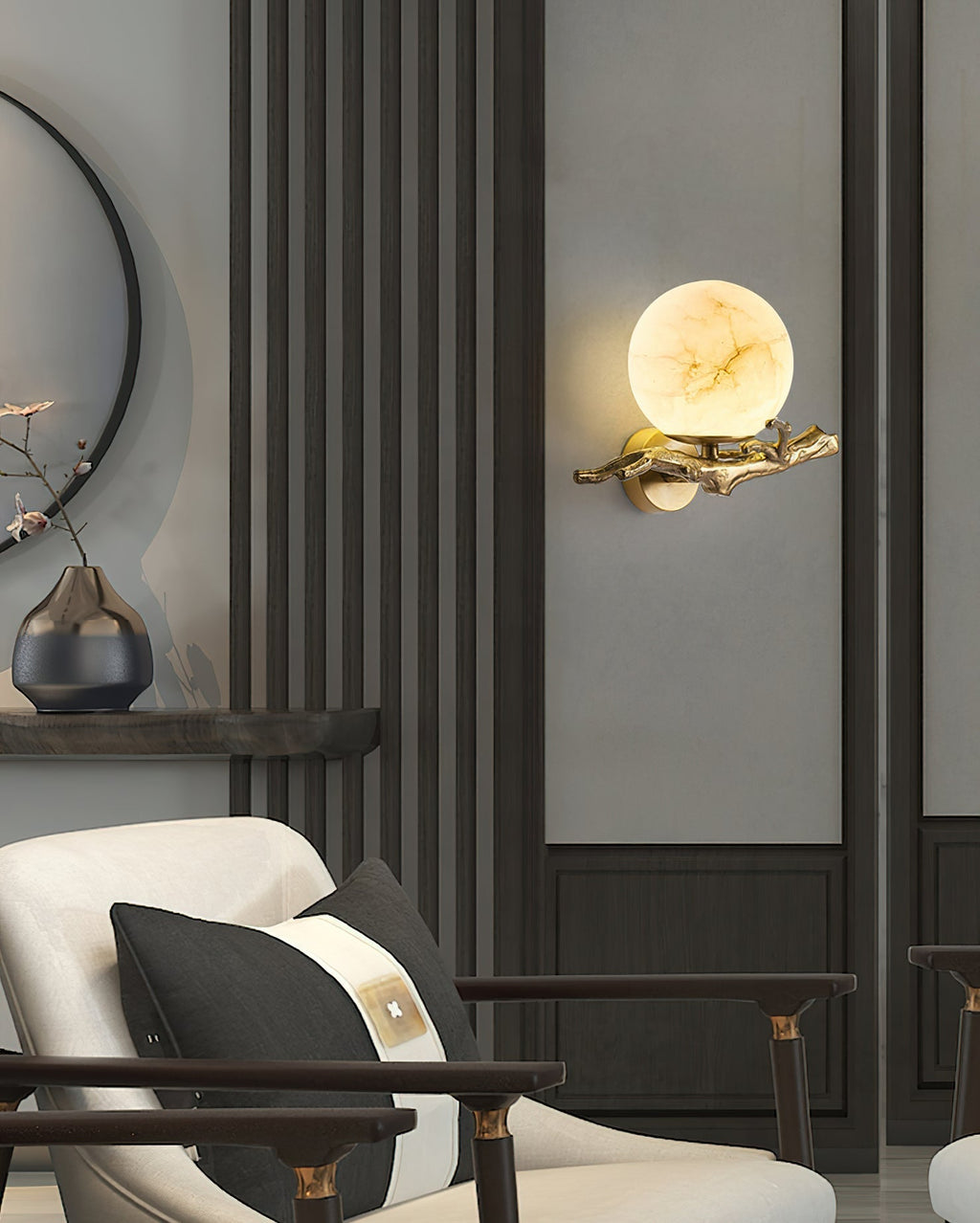 The Clérachic Alabaster Globe Wall Sconce set on a panelled grey wall in a sitting room, warm light washing the panel behind it.