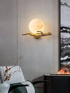 Clérachic Alabaster Globe Wall Sconce lit against a pale limewashed panel, the brass branch throwing a fine shadow across the wall.