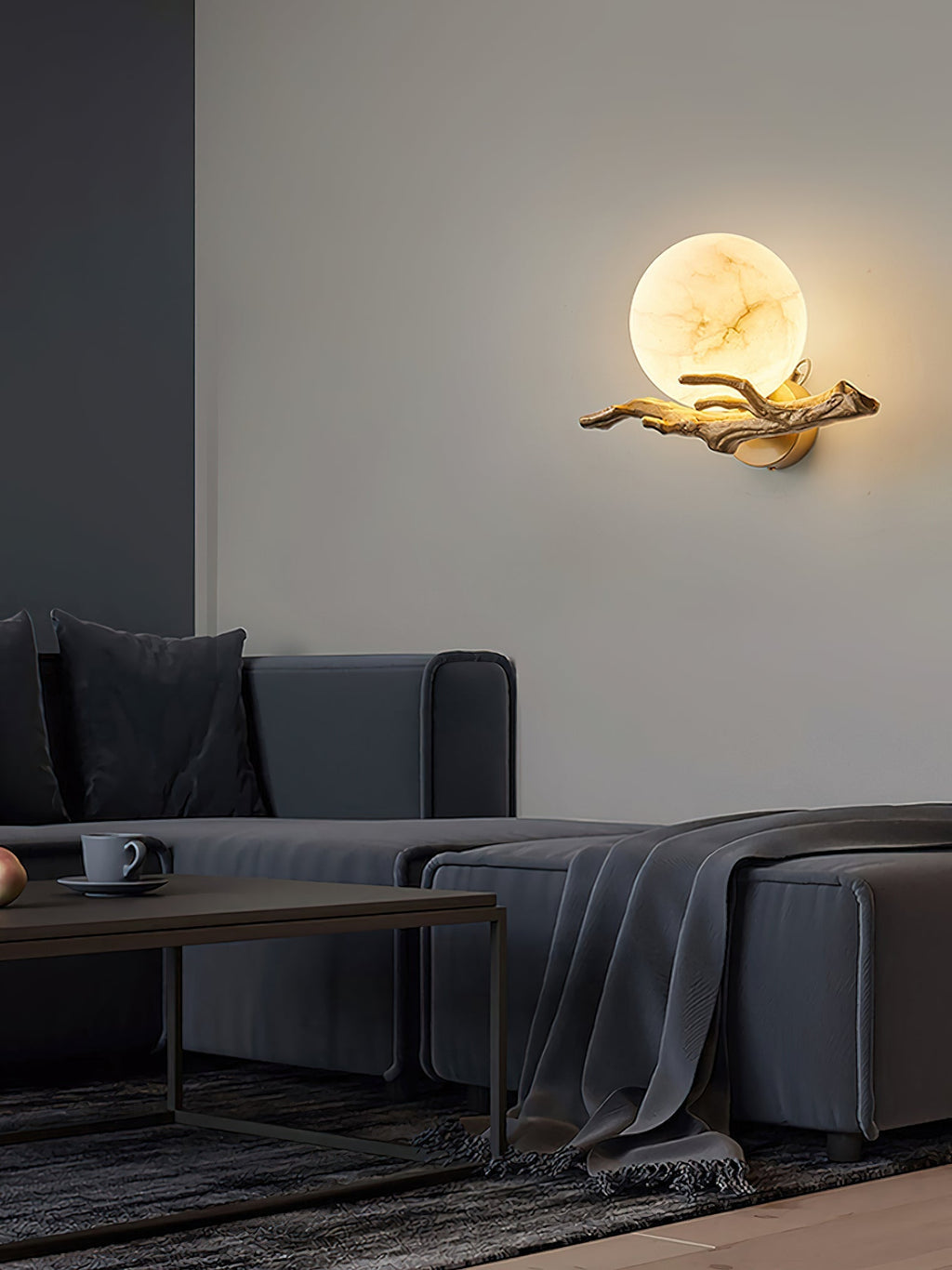 The Clérachic Alabaster Globe Wall Sconce seen from across a living room, one warm globe balanced on its outstretched brass branch.