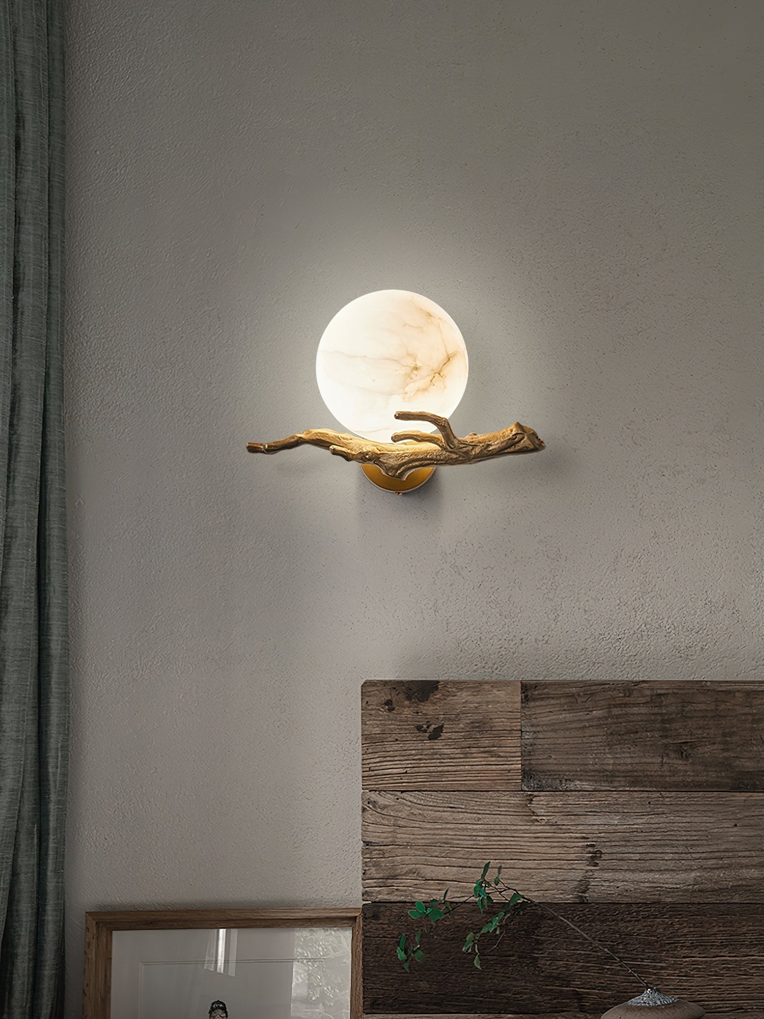 Clérachic Alabaster Globe Wall Sconce above a reclaimed timber headboard, the lit globe reading like a full moon on rough plaster.
