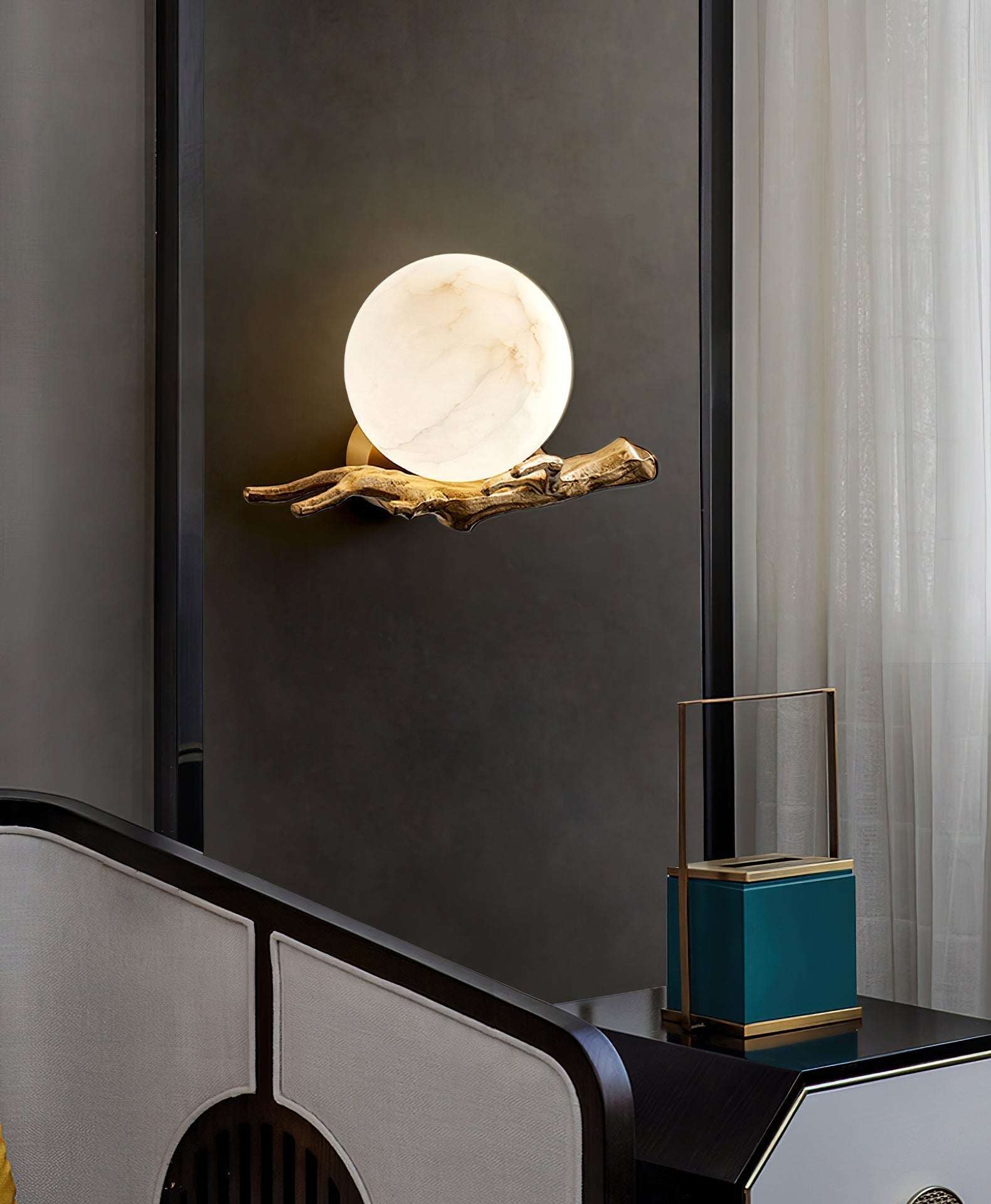 The Clérachic Alabaster Globe Wall Sconce against a dark charcoal panel, the alabaster ball bright and the arm in silhouette.