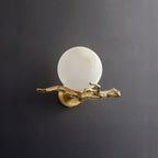 Clérachic Alabaster Globe Wall Sconce unlit on a dark grey ground, the polished brass branch running the full width of the piece.
