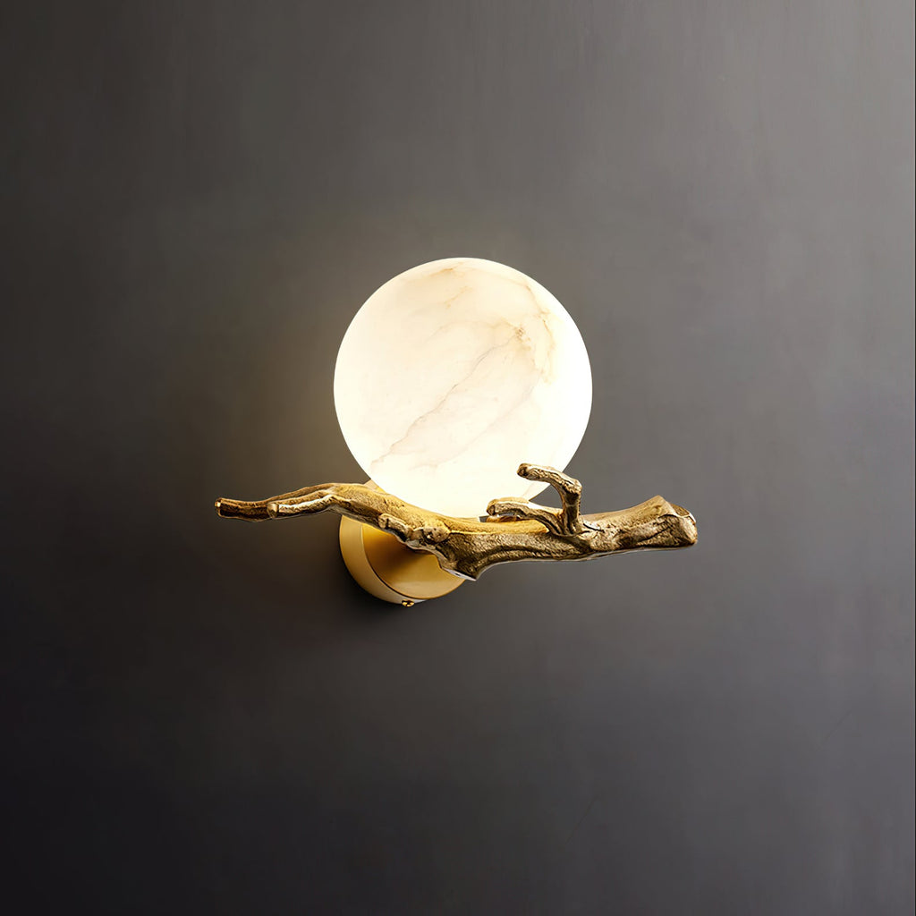 The Clérachic Alabaster Globe Wall Sconce lit on a dark grey ground, warm light bleeding out around the veined alabaster ball.